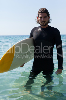 Surfer with surfboard standing at beach coast