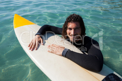 Surfer leaning on surfboard in sea