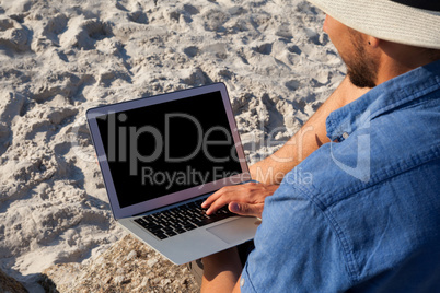 Man using laptop on the beach