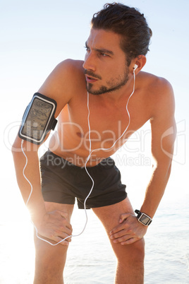 Exhausted man taking a break after jogging on beach