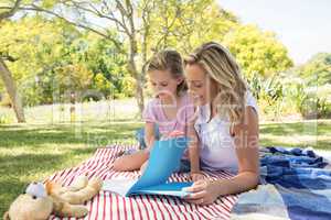 Mother and daughter reading book in park