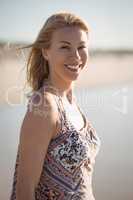 Portrait of smiling young woman standing at beach