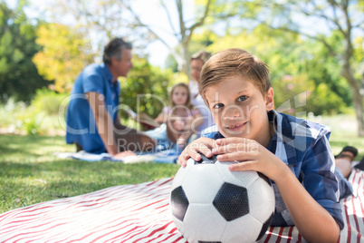 Smiling boy leaning on his football in picnic at park