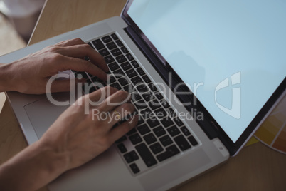 Cropped hands of businesswoman working on laptop