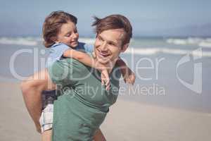 Happy father piggybacking his son at beach