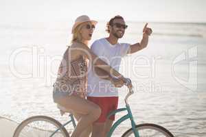 Happy couple riding bicycle at beach