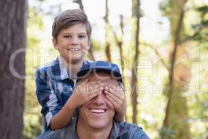 Portrait of boy covering fathers eyes
