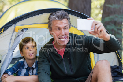 Playful father and son taking selfie in tent