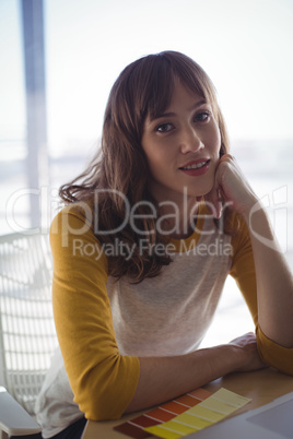 Portrait of businesswoman leaning on desk at office