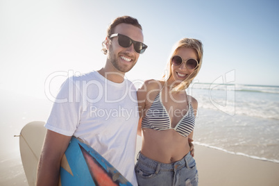 Portrait of happy young couple wearing sunglasses at beach