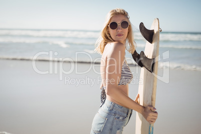 Side view of woman holding surfboard at beach