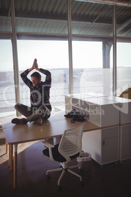 Businessman meditating on desk at office
