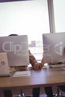 Business couple holding hands behind computers in office