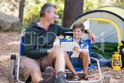 Cheerful father and son using digital tablet in forest