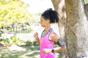 Female jogger listening to music while jogging in the park