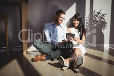 Happy executives sitting on floor and using mobile phone