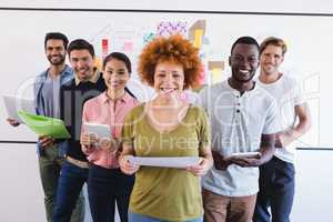 Portrait of smiling colleagues standing against whiteboard