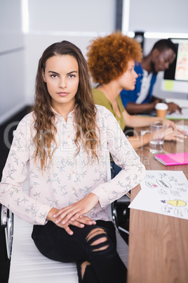 Portrait of businesswoman with colleagues at desk