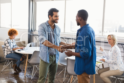 Happy business people shaking hands at creative office
