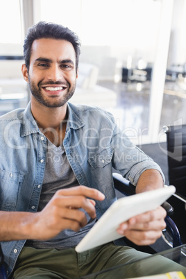 Portrait of smiling businessman using digital tablet while sitting on wheelchair