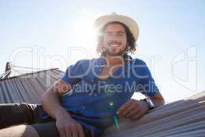 Portrait of smiling man relaxing on hammock at beach