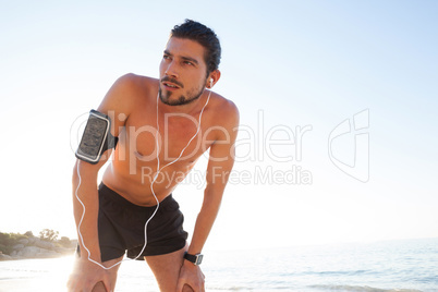 Exhausted man taking a break after jogging on beach