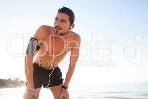 Exhausted man taking a break after jogging on beach