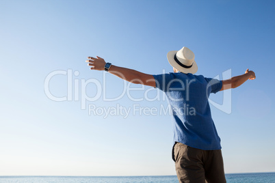 Man standing at beach with arms outstretched