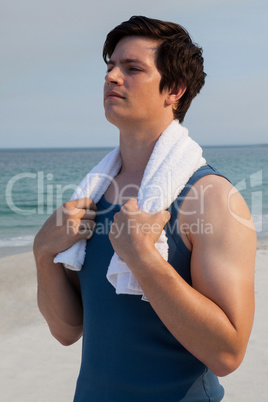 Thoughtful man with towel standing at beach