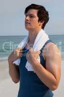 Thoughtful man with towel standing at beach