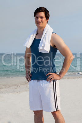 Smiling man standing on beach with towel around his neck