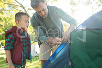 Father and son setting up the tent at campsite