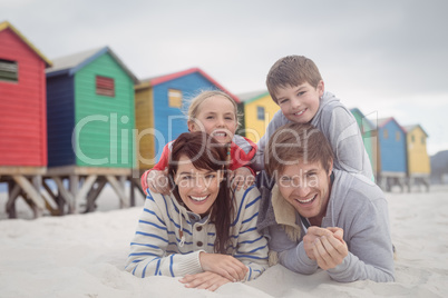 Portrait of happy parents with children lying on sand