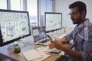 Businessman using mobile phone while working in office
