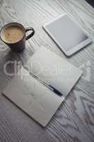 Digital tablet with coffee cup and book on table