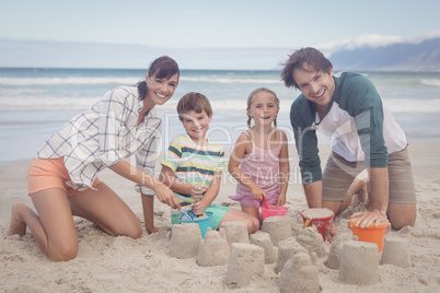 Portrait of happy family making sand castle