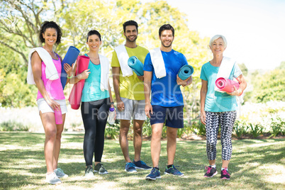 Group of people standing in the park with rolled exercise mats