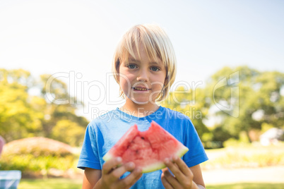 Smiling boy holding watermelon in the park