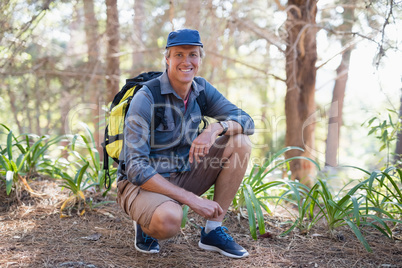 Portrait of hiker kneeling on trail against trees