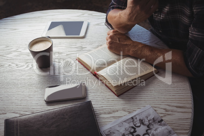 Mid section of businessman reading book on table