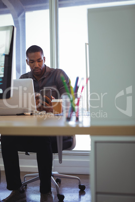 Businessman texting with mobile in creative office
