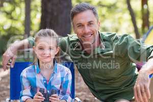 Happy father and daughter sitting at campsite in forest