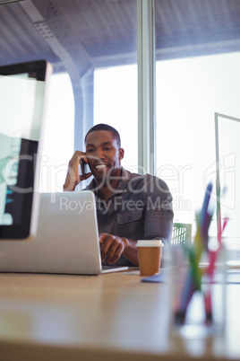 Smiling businessman talking on phone in creative office
