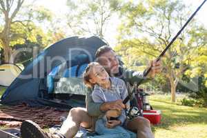 Father and daughter holding a fishing rod outside the tent