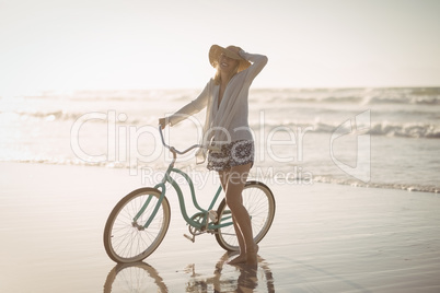 Full length of woman standing by bicycle on shore at beach