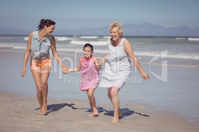 Happy multi-generation family running while holding hands at beach