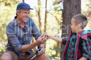 Boy giving pine cone to father in forest