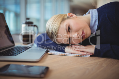 Portrait of tried executive leaning on desk