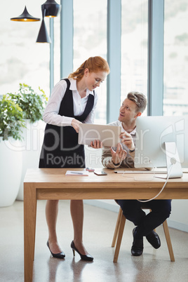 Executives discussing over laptop at desk