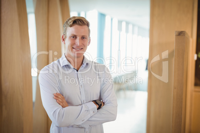 Portrait of smiling executive standing with arms crossed